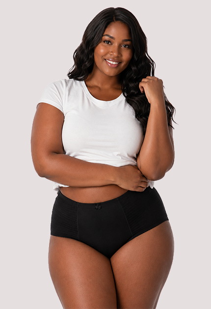 Woman wearing a white t-shirt and black high-waisted underwear on a plain background