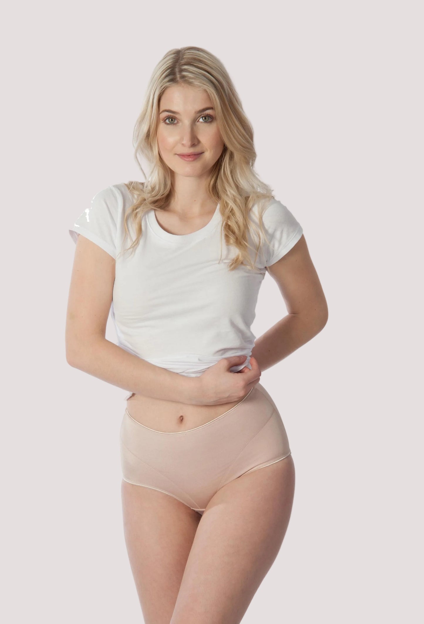 Woman wearing a white t-shirt and beige underwear on a white Joseph Rufina women’s silky microfiber high cut brief in nude background