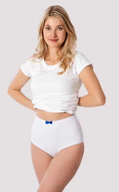 A woman modeling white high-waisted briefs with a small blue bow detail at the waistband, paired with a white cropped t-shirt, against a plain white background.